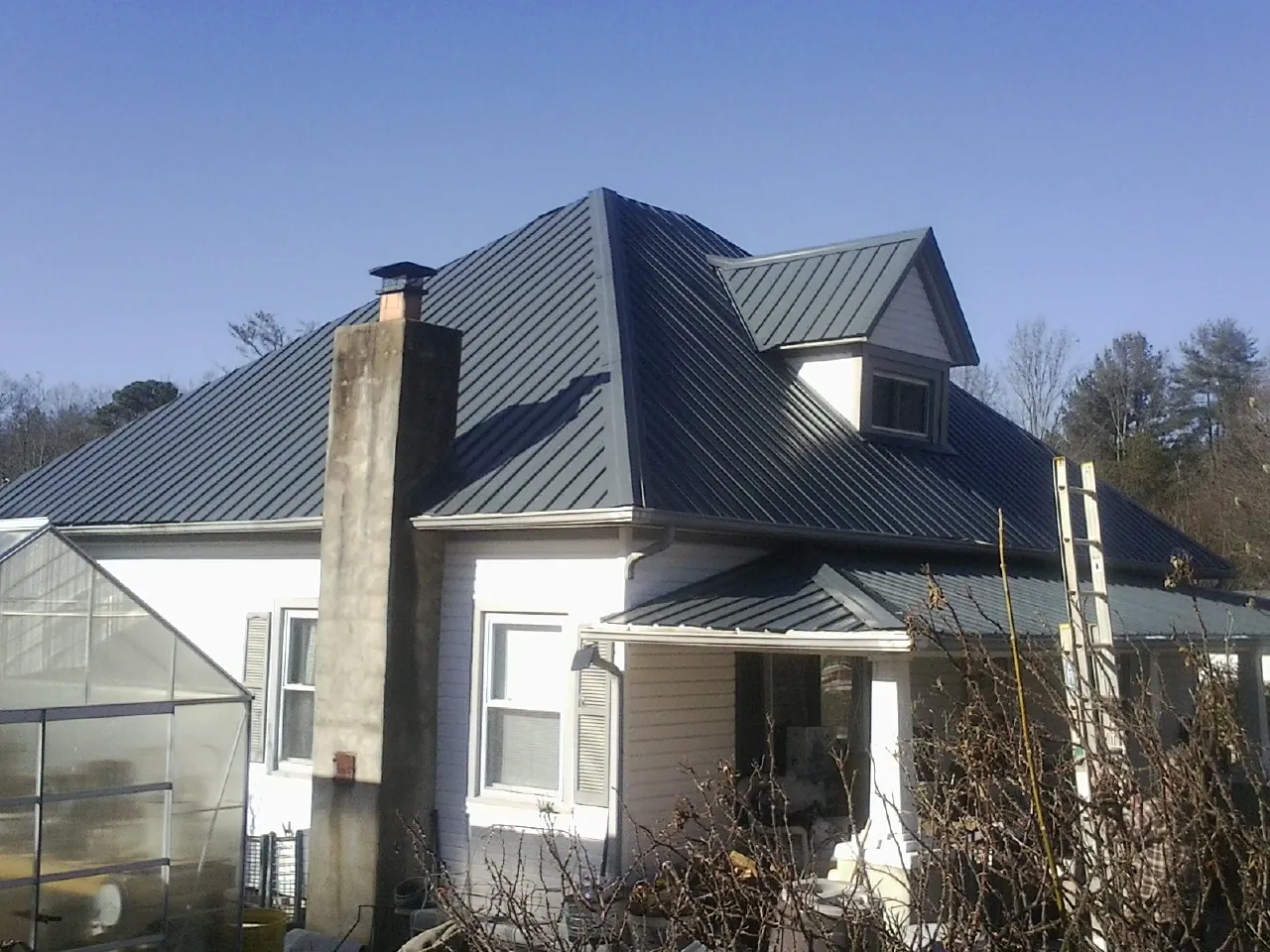 Dark blue standing seam metal roof on a white farmhouse with dormer — Slate & Tile Roof Repair by Roofing Brothers in Louisa
