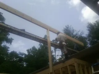 Carpenter setting a ridge beam over a new addition frame — Ice Dam Removal by Roofing Brothers in Louisa