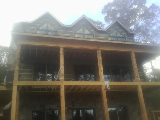 Dormers and porch framing on a large log home under construction — Roof Coating work by our crew in Louisa