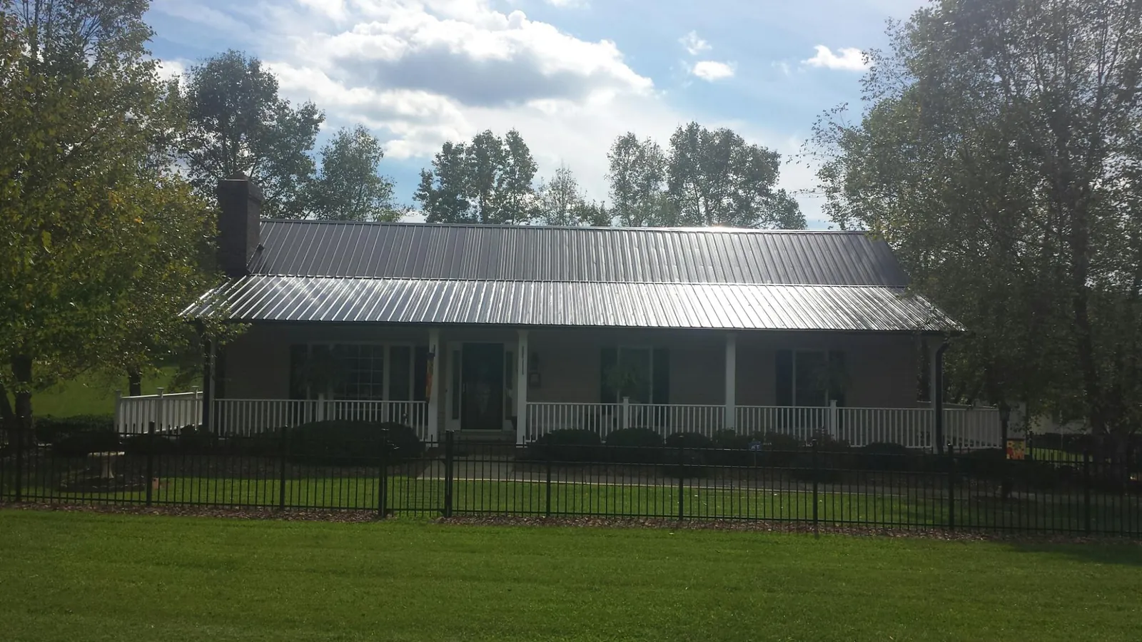 Gray metal roof on a brick ranch with a full width front porch — Gutter Guard Installation work by our crew in Louisa