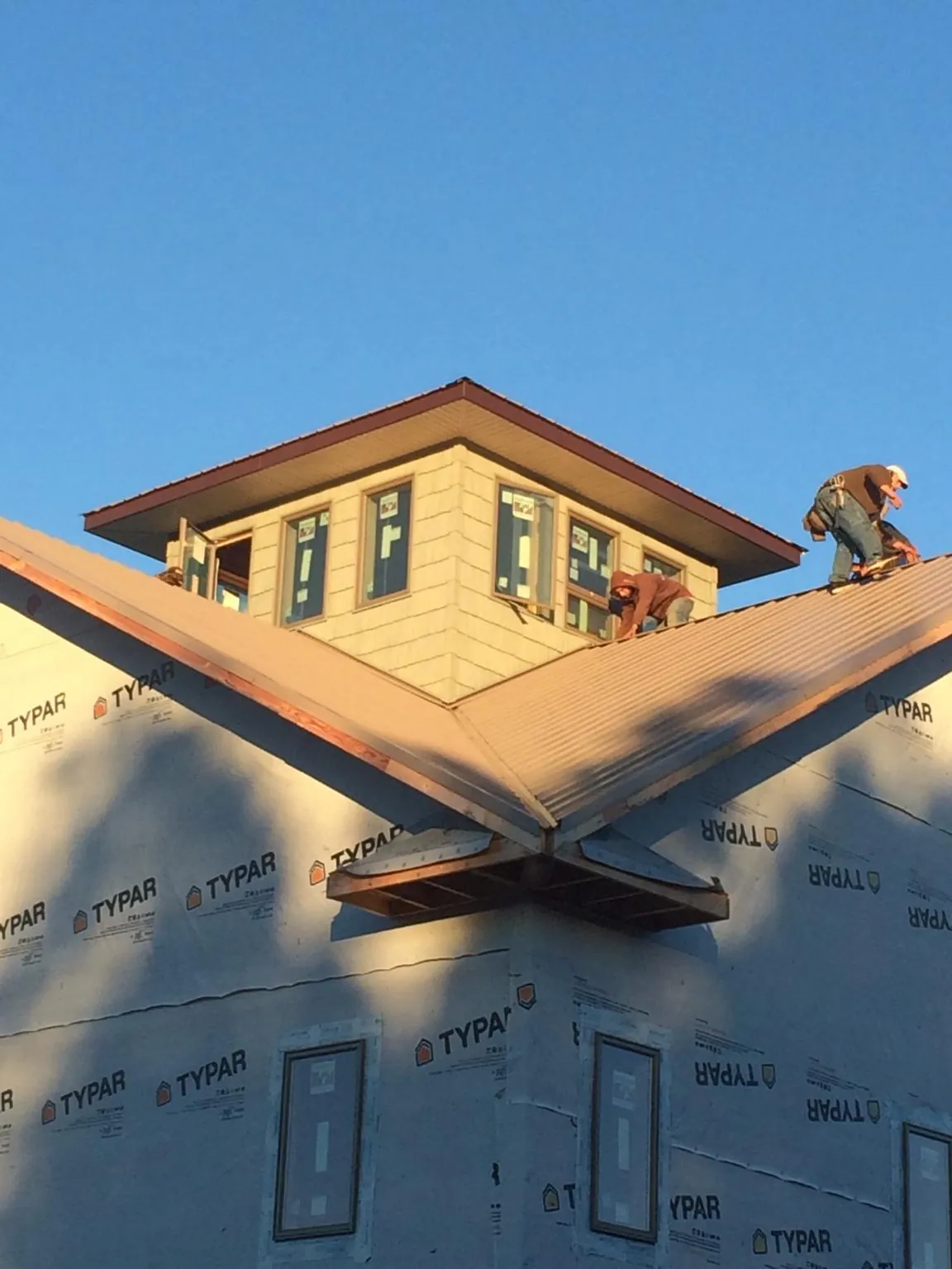 Roofers working around a rooftop cupola on a new metal roof at sunset — Roof Waterproofing in Louisa by Roofing Brothers